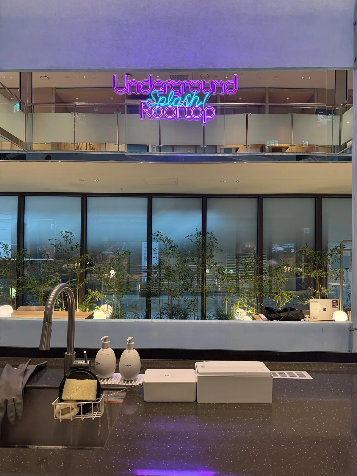 캔틴 싱크대 너머로 보이는 'Underground Splash! Rooftop' 네온사인