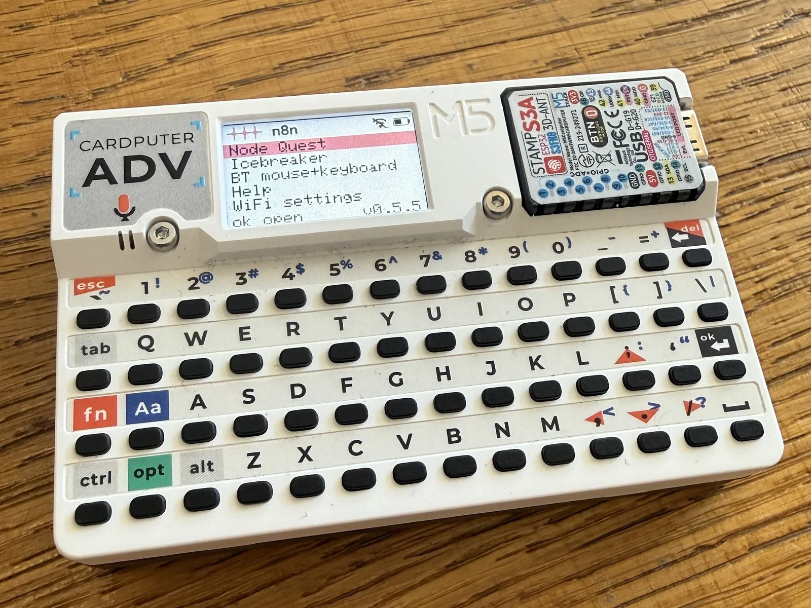 My Cardputer ADV on my desk. The screen shows the event loader menu (Node Quest, Icebreaker, BT mouse+keyboard)
